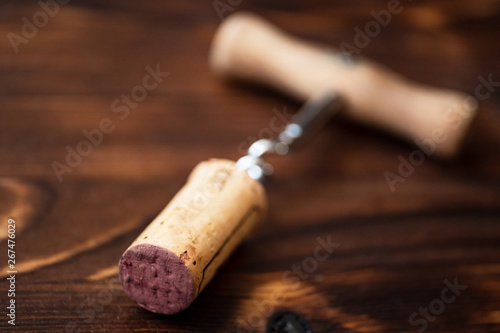 Corkscrew and a twisted cork on a wooden background.
