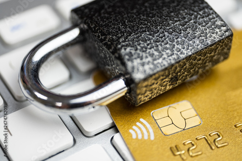 Concept of security of electronic payment. Lock on gold credit card and white keyboard. photo