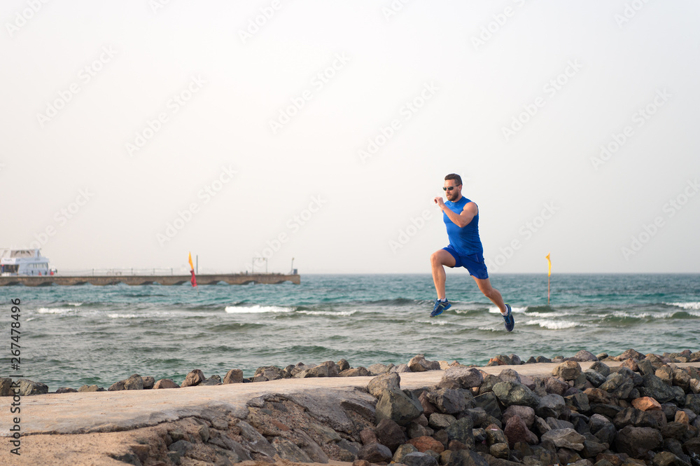 athlete runner along sea coast. running to success. summer vacation. copy space. speed concept. goal and future. people and nature. man runner focused on achievement. life as marathon or sprint