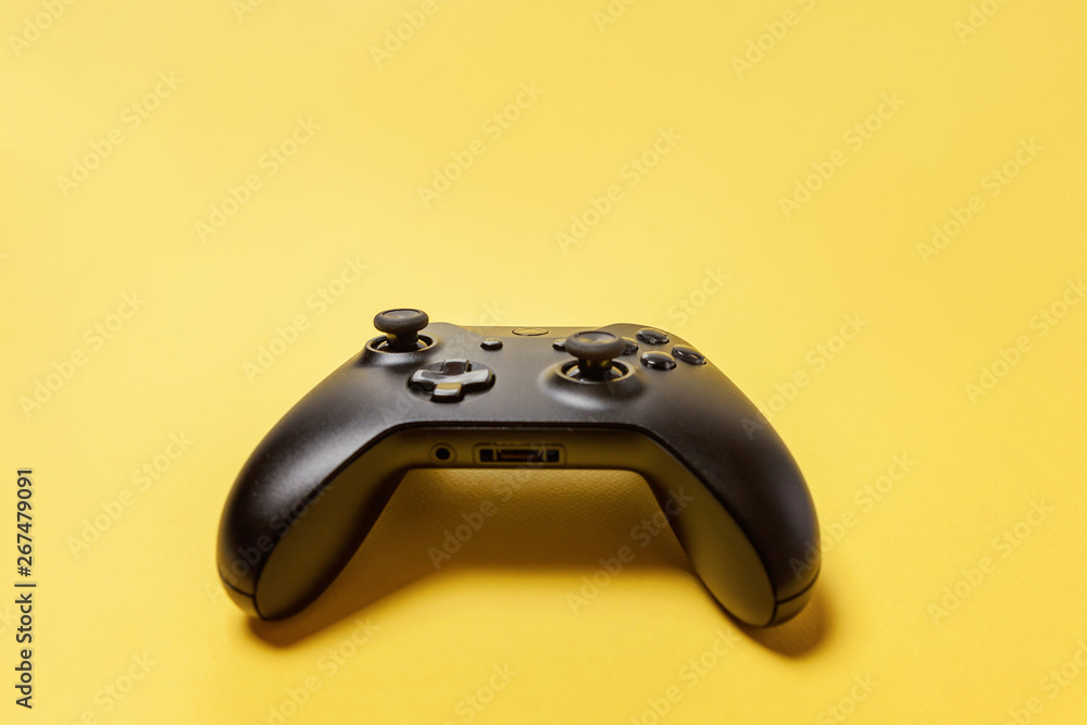 Black joystick gamepad, game console on yellow colourful trendy modern fashion pin-up background. Computer gaming competition videogame control confrontation concept. Cyberspace symbol Black joystick gamepad, game console on yellow colourful trendy modern fashion pin-up background. Computer gaming competition videogame control confrontation concept. Cyberspace symbol