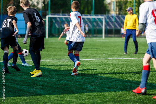 Boys at black white sportswear run, dribble, attack on football field. Young Soccer players with ball on green grass. Training, football, active lifestyle for kids   © Natali