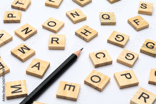 Black pencil and scattered alphabet letters on wooden blocks on white background