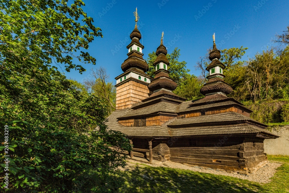 Prague, Czech Republic - April 22 2019: Church of the Archangel Michael built in 18th century with shingled roof, made of wooden logs standing at Kinsky garden. Sunny spring day, blue sky.