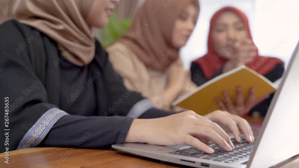 Young beautiful woman veiled when sitting with laptop, tablet, and book in the house working together with friend Young beautiful woman veiled when sitting with laptop, tablet, and book in the house working together with friend