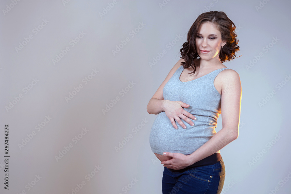 A woman waiting for a baby. Pregnant woman in jeans and t-shirt. Pregnancy. Gestation a baby. A woman waiting for a baby. Pregnant woman in jeans and t-shirt. Pregnancy. Gestation a baby.
