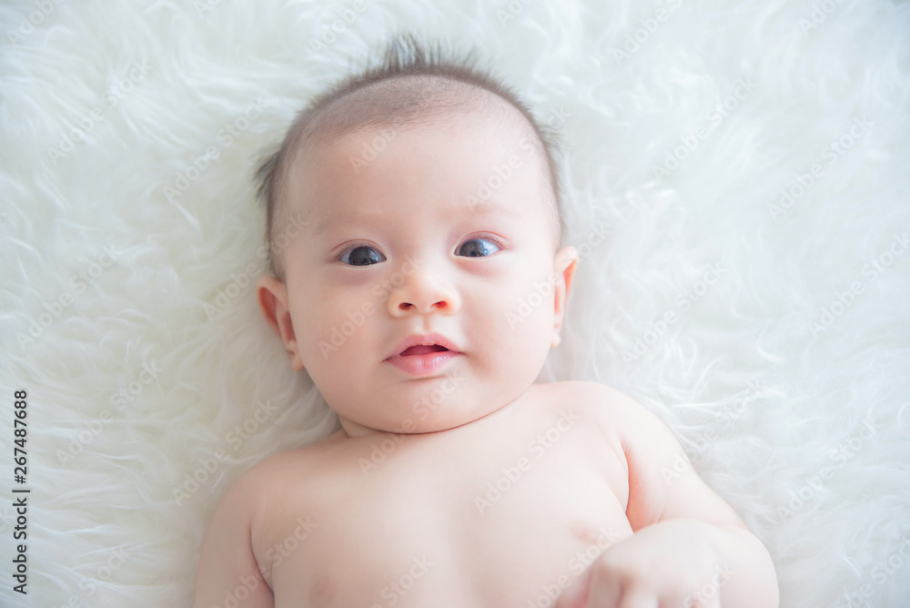 Little asian baby lying on bed and looking at camera Little asian baby lying on bed and looking at camera