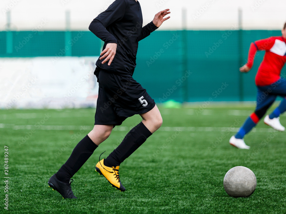 Boys at black red sportswear run, dribble, attack on football field. Young  soccer players with ball on green grass. Training, football, active  lifestyle for kids Stock Photo | Adobe Stock