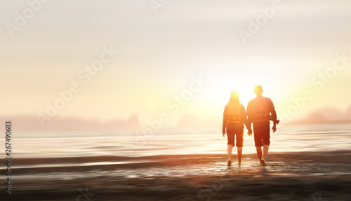Couple walking on beach at sunset. Romantic summer travel holidays background.