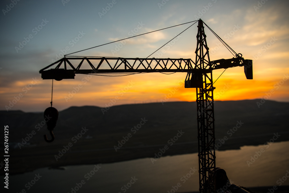 Abstract Industrial background with construction crane silhouette over amazing sunset sky. Tower crane against the evening sky. Industrial skyline