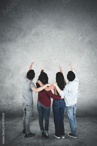 Young people point at copy space together © Creativa Images