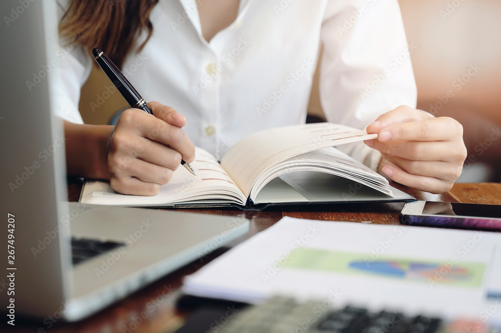 Closeup image female hand holding pen and writing on diary. Closeup image female hand holding pen and writing on diary.
