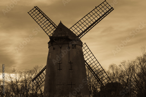 Ancient Windmill in the United Kingdom. Old photograph style. Taken From the rear of the historic building .  A cloudy sky and distant trees. photo