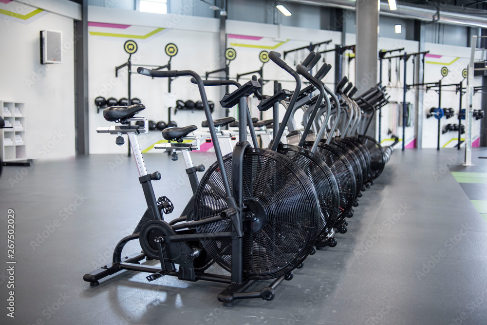 Row of elliptical bikes or assault air bikes in a gym or fitness Club Row of elliptical bikes or assault air bikes in a gym or fitness Club