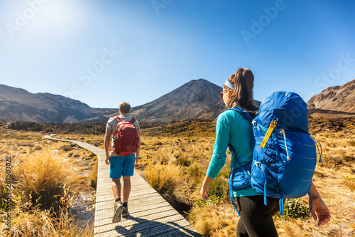 New Zealand Hiking Couple Backpackers Tramping At Tongariro National Park. Male and female hikers hiking by Mount Ngauruhoe. People living healthy active lifestyle outdoors photo