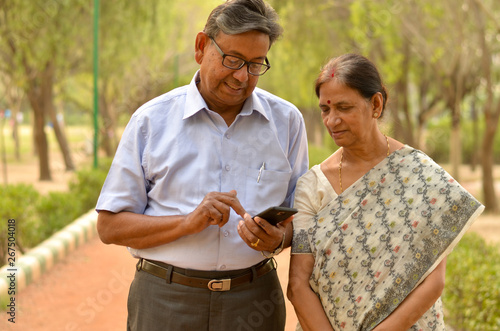 Wallpaper Mural Senior couple in park looking at  their smart phone and smiling in Delhi, India Torontodigital.ca