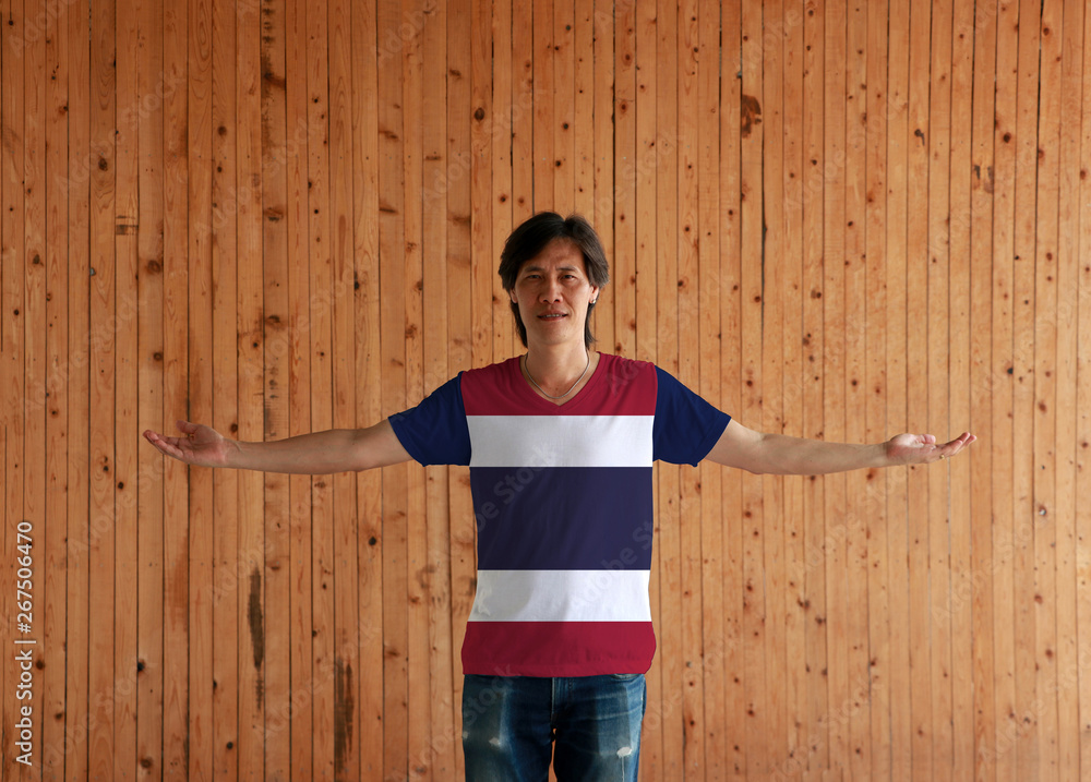 Man wearing Thailand flag color shirt and standing with arms wide open on the wooden wall background. Man wearing Thailand flag color shirt and standing with arms wide open on the wooden wall background.