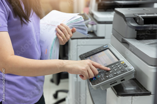 Foto Bussinesswoman using copier machine to copy heap of paperwork in office