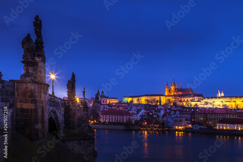 Looking along the Charles Bridge toward the illuminated St. Vitus Cathedral and Prague Castle at twilight