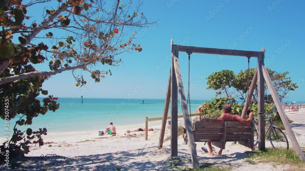 Beach goer relaxing on a beach swing on Honeymoon Island, FL Beach goer relaxing on a beach swing on Honeymoon Island, FL