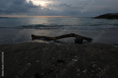 A piece of wood on the sand of Kuta Bali beach which was photographed at dusk, with beautiful sky colors