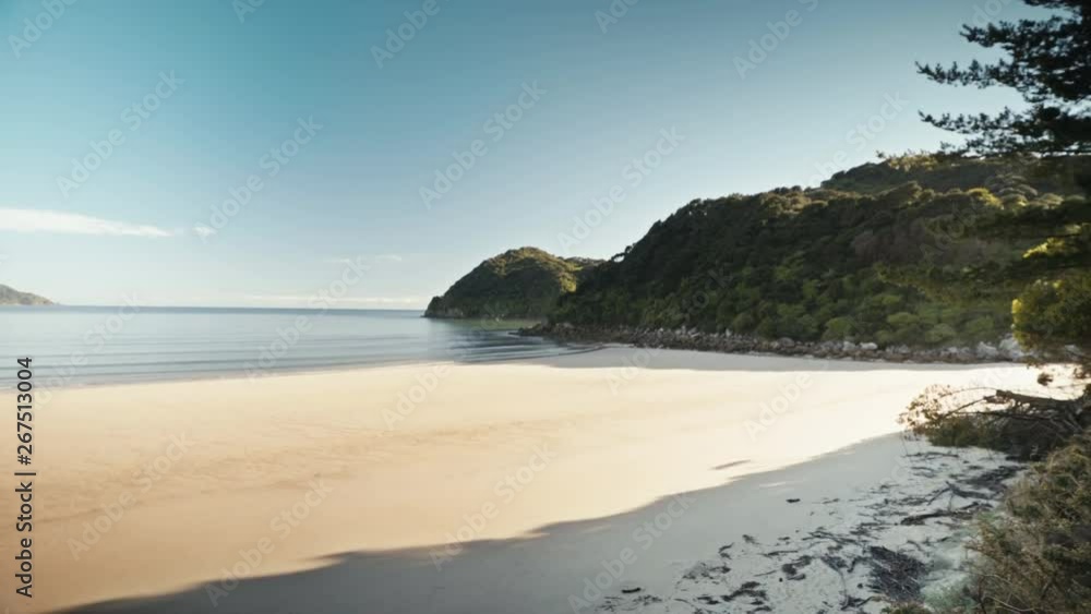 Wide shot of an empty sandy beach clear water green hills Wide shot of an empty sandy beach clear water green hills