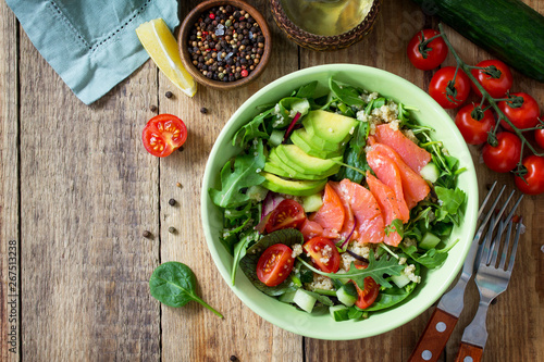Diet menu, Vegan food. Healthy salad with quinoa, arugula, Tomatoes, Salmon and Avocado on rustic table. Top view flat lay.  Free space for your text.