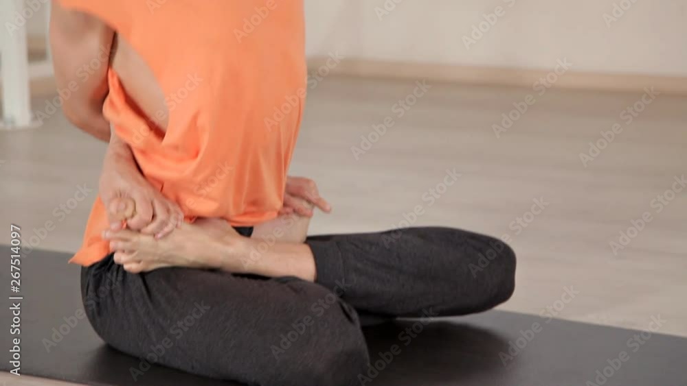 Young athletic man sitting in yoga pose on blue Mat in gym with mirrors. Yoga, sport, relaxation, flexible Young athletic man sitting in yoga pose on blue Mat in gym with mirrors. Yoga, sport, relaxation, flexible