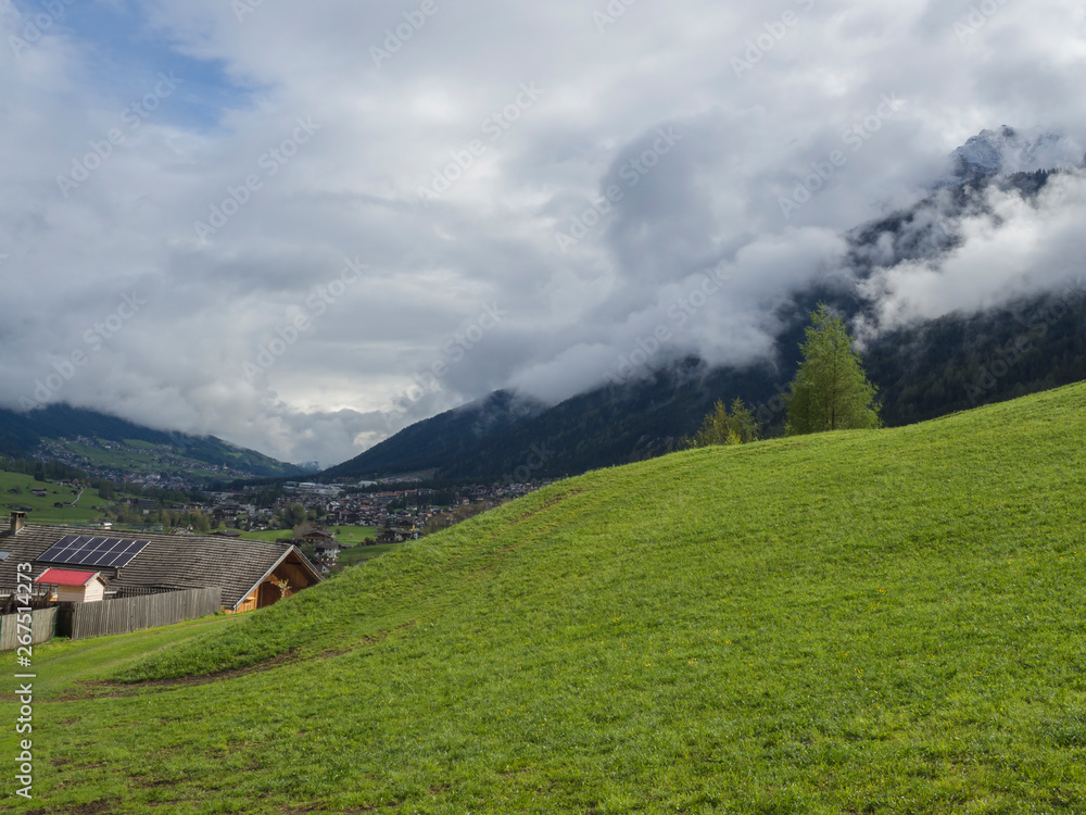 Lush green meadow,Idyllic spring mountain rural landscape. View over Stubaital or Stubai Valley near Innsbruck, Austria with village Neder, white clouds and fog.
