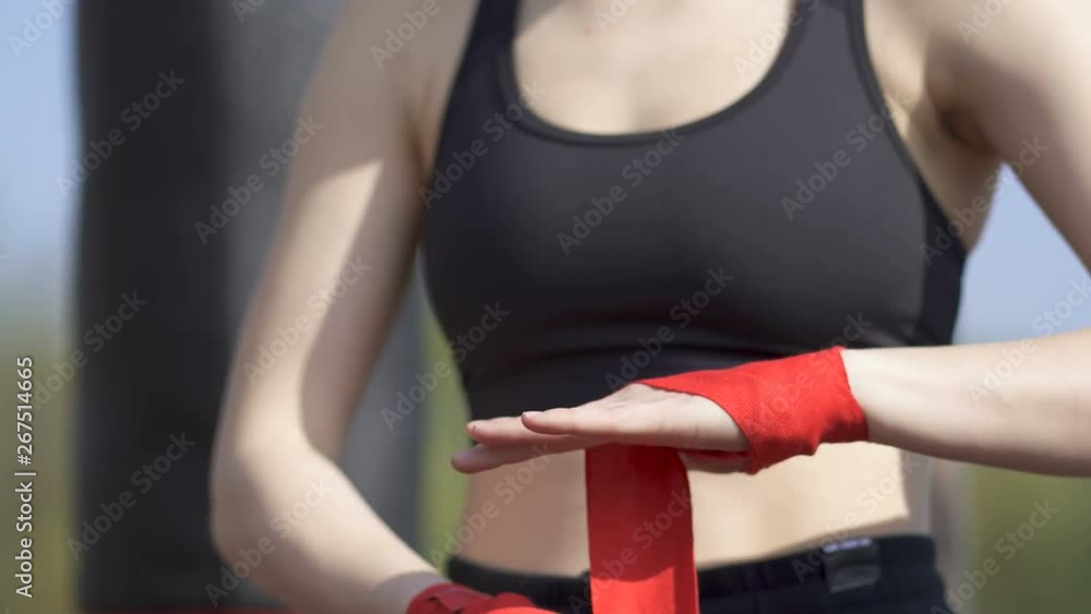 4k.Woman boxer, kickboxer reels up bandage on hand on street training ground. Close up 4k.Woman boxer, kickboxer reels up bandage on hand on street training ground. Close up