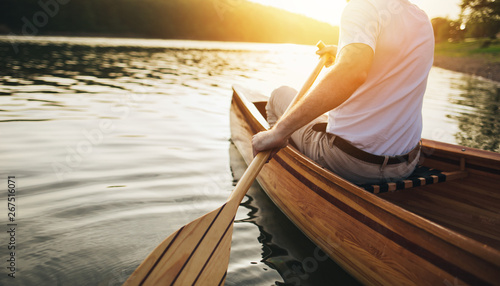Tableau sur toile Canoeing. Close up of man holding canoe paddle at sunset lake
