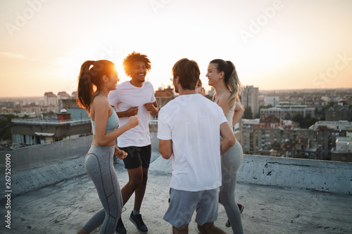 Group of fit healthy friends, people exercising together outdoor on rooftop
