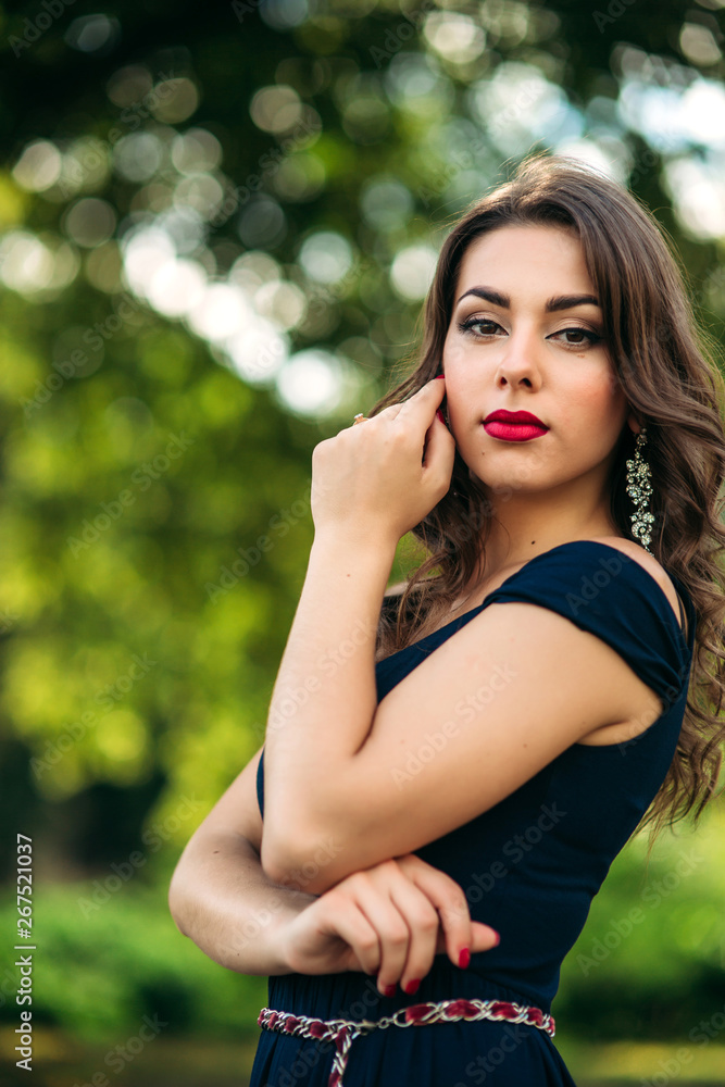 Close up portrait of woman with evening makeup. Woman close her eyes and show fahion slyle. Backgrounf of blue and green bokeh