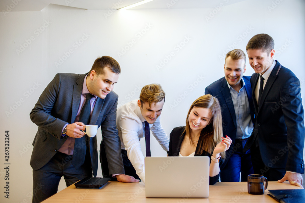 Woman sitting at the desk, the team is standing around her. Woman sitting at the desk, the team is standing around her.