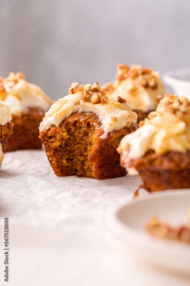 Carrot cupcakes with cream cheese frosting and caramel topping with pecans, close up, selective focus Carrot cupcakes with cream cheese frosting and caramel topping with pecans, close up, selective focus