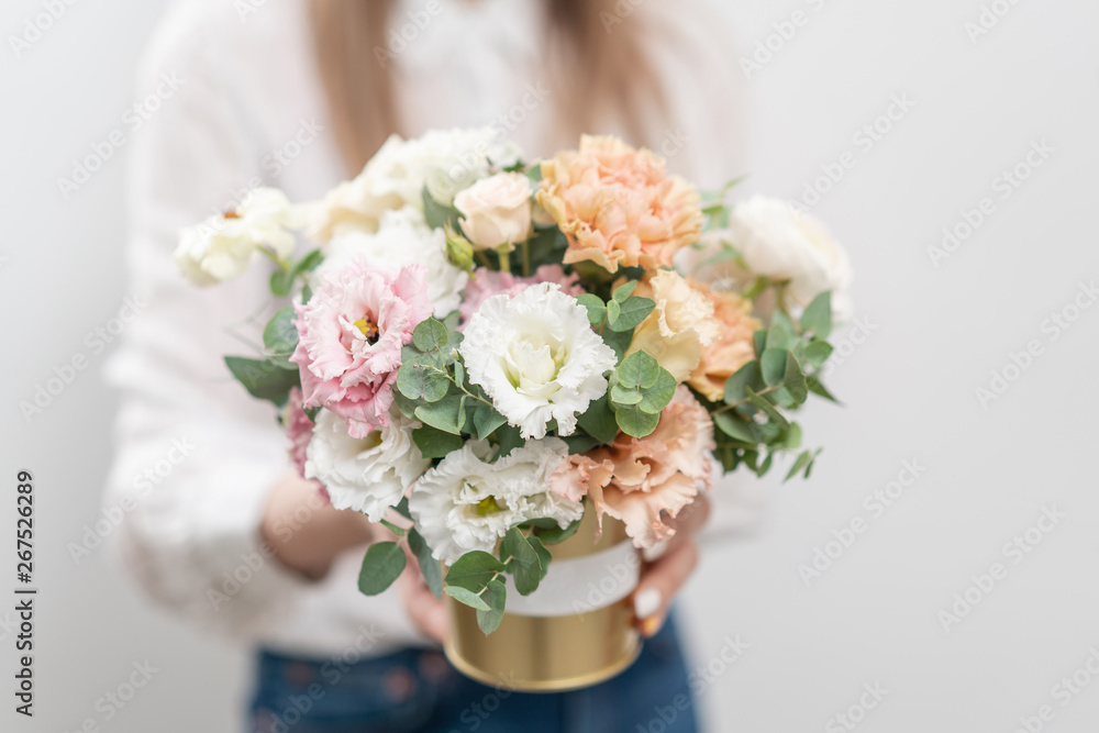 Beautiful floral arrangement of mixed flowers in woman hand. Golden flowerpot. The work of the florist at a flower shop. Delicate Pastel color. Fresh cut flower.