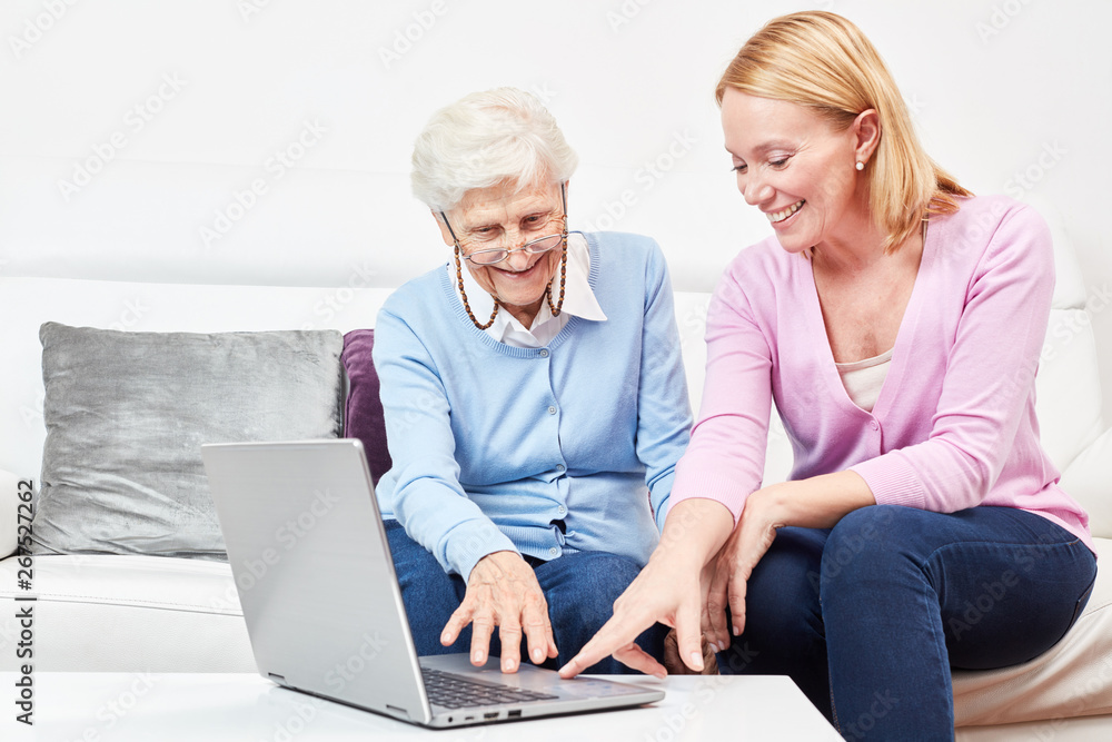 Junge Frau erklärt einer Seniorin einen Laptop