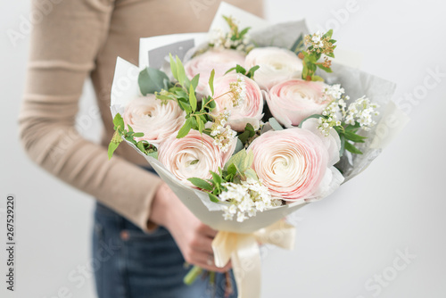 Mono bouquet of Ranunculus, Persian Buttercup. Delicate bouquet of mixed flowers in womans hands. the work of the florist at a flower shop. Delicate Pastel color. Fresh cut flower.