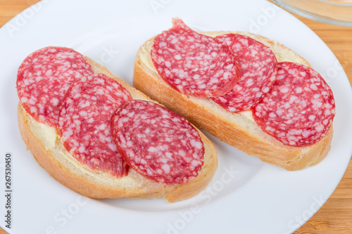 Open sandwiches with salami on dish close-up