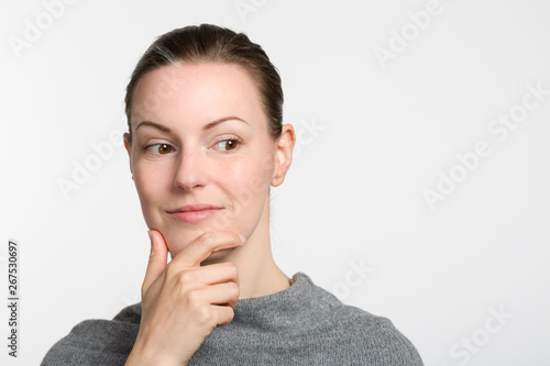 young woman with hand at her chin is thinking about