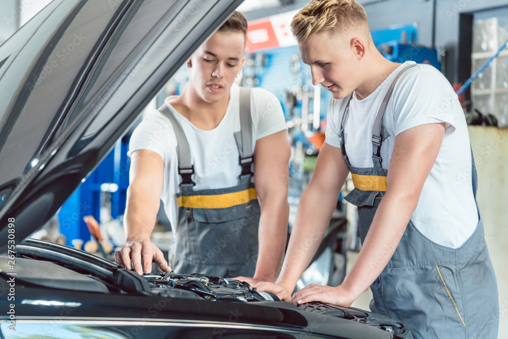 Experienced auto mechanic checking the parts of a car in a modern repair shop Experienced auto mechanic checking the parts of a car in a modern repair shop