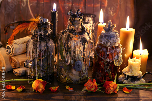 Witch vintage bottles with candles and ancient paper scrolls © samiramay