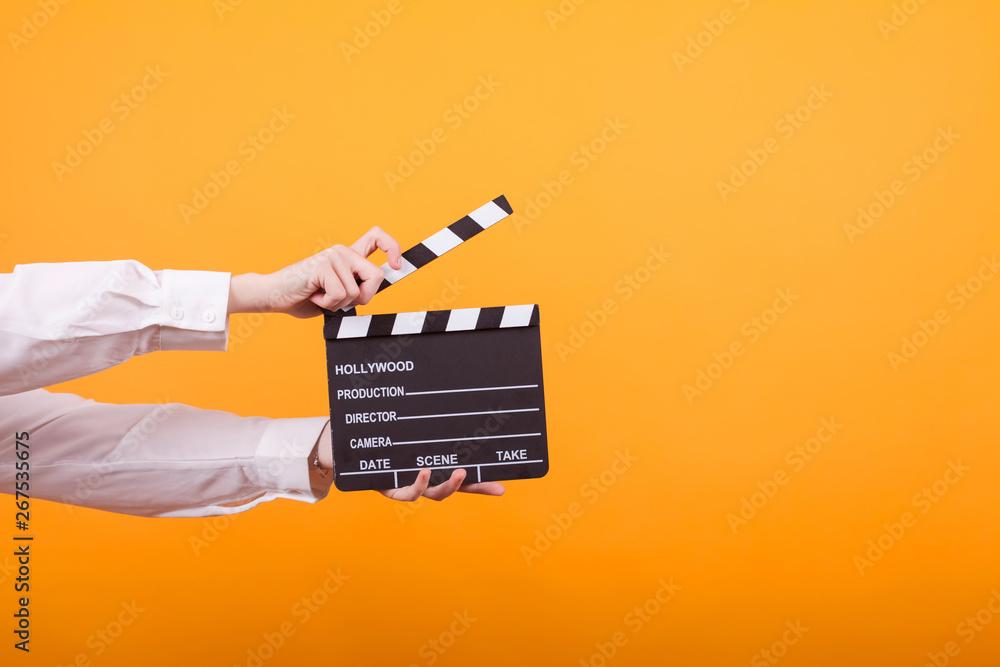 Naklejka premium Shot of isolated hands on yellow background holding a clapper