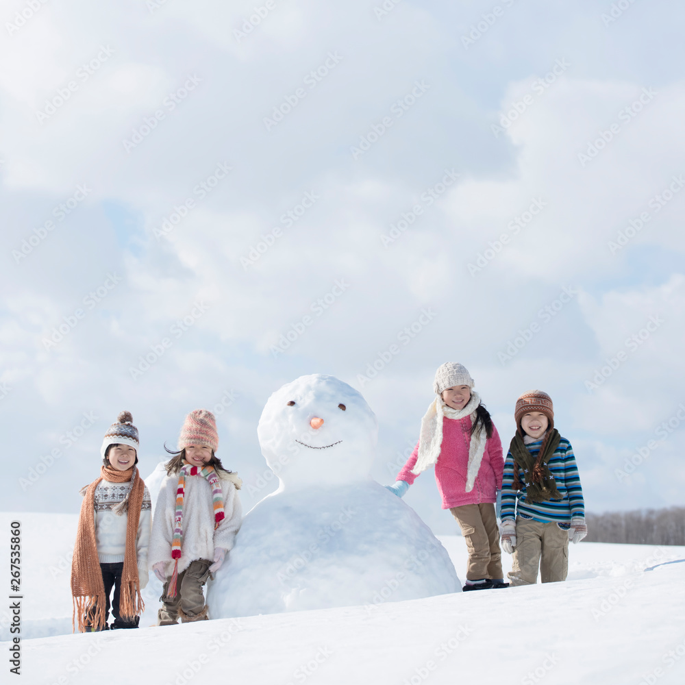 雪だるまの周りで微笑む小学生