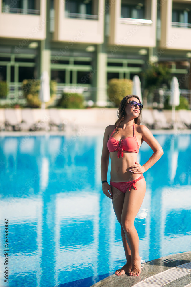 Beautiful and sexy woman stand in front of sweimming pool at the resort