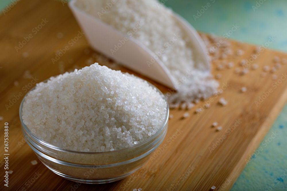 Sugar in glass bowl on wooden background Sugar in glass bowl on wooden background