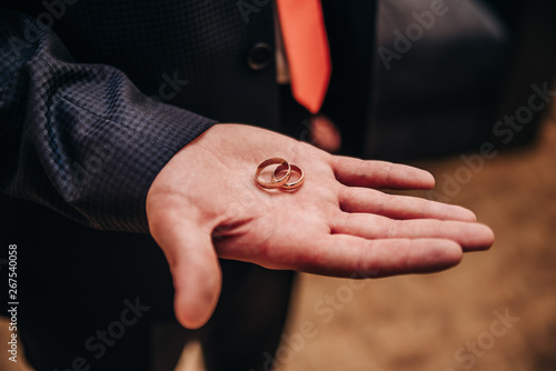 gold wedding rings on the palm of the groom
