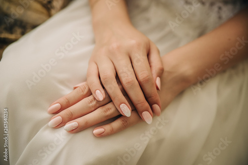 beautiful hands of a girl on a white wedding dress