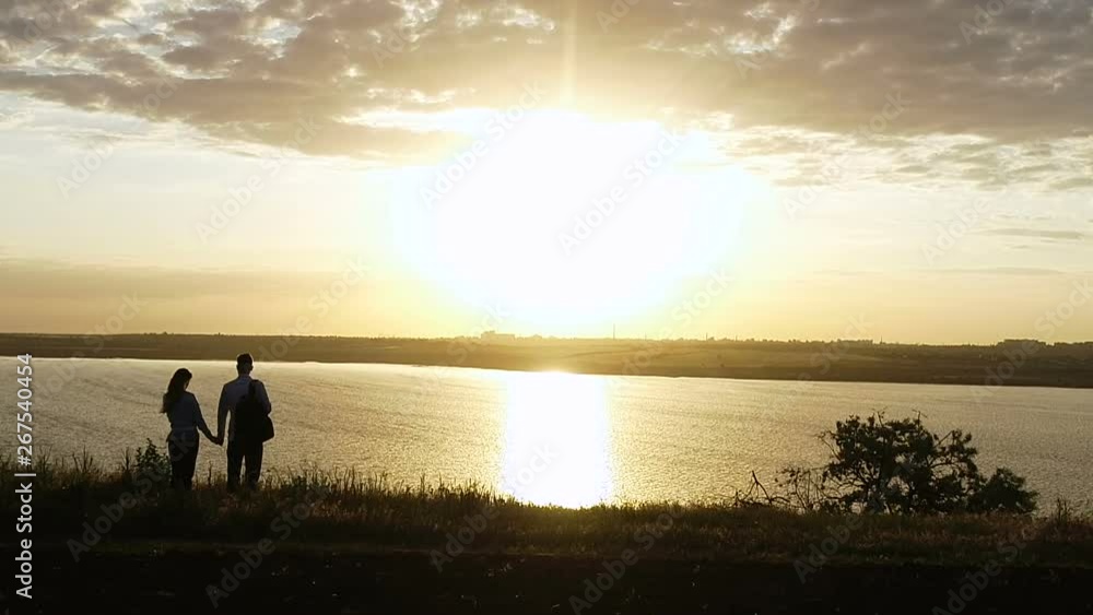 lovers admire the sunset, walk on the river bank, look into the distance lovers admire the sunset, walk on the river bank, look into the distance