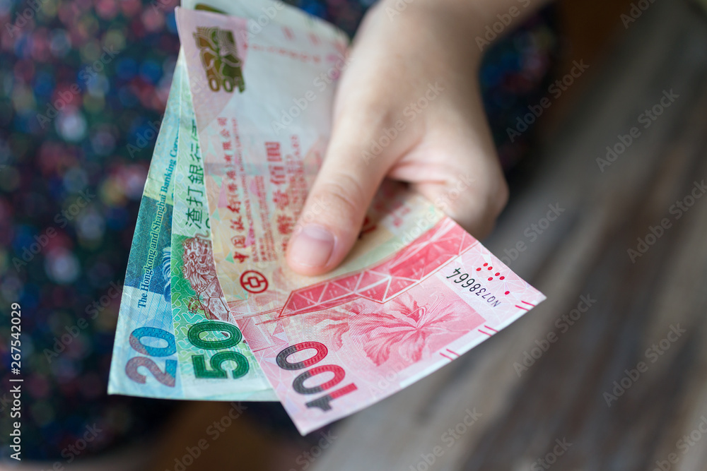 A hand giving Hong kong dollars (HKD) in cash