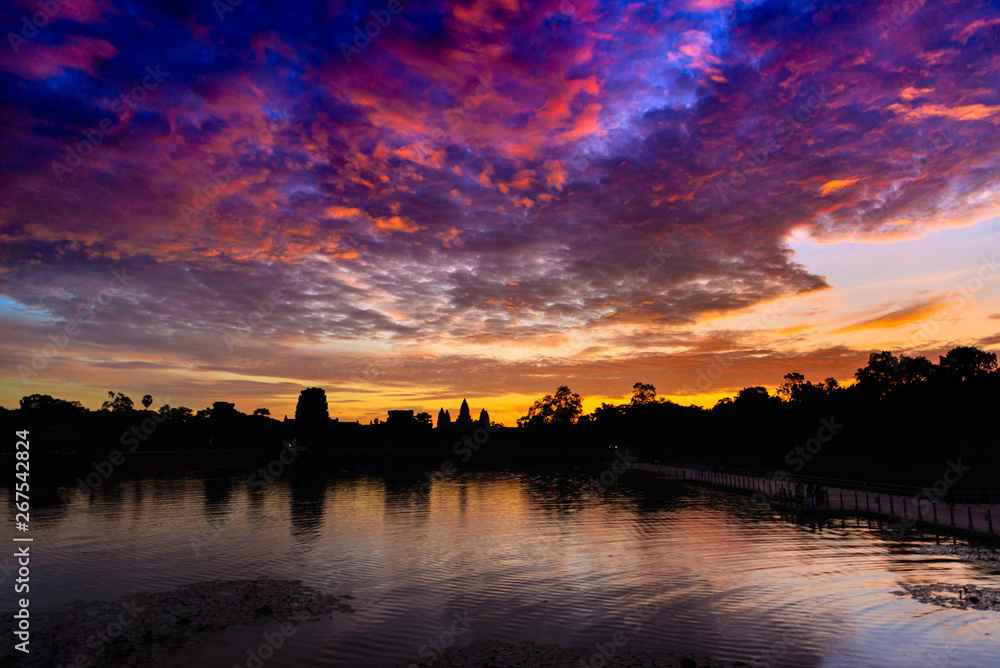 Angkor Wat dramatic sky at dawn main facade silhouette reflection on water pond. World famous temple in Cambodia. Angkor Wat dramatic sky at dawn main facade silhouette reflection on water pond. World famous temple in Cambodia.